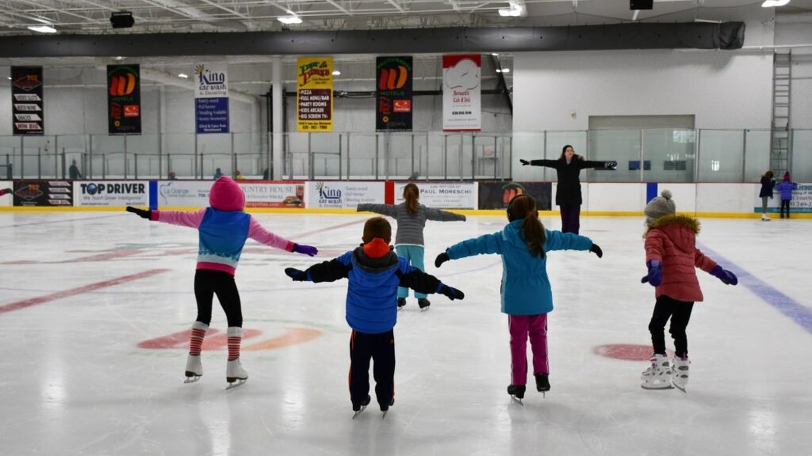 Children ice skating with instructor at Pines Ice Arena indoor rink in Pembroke Pines, Florida