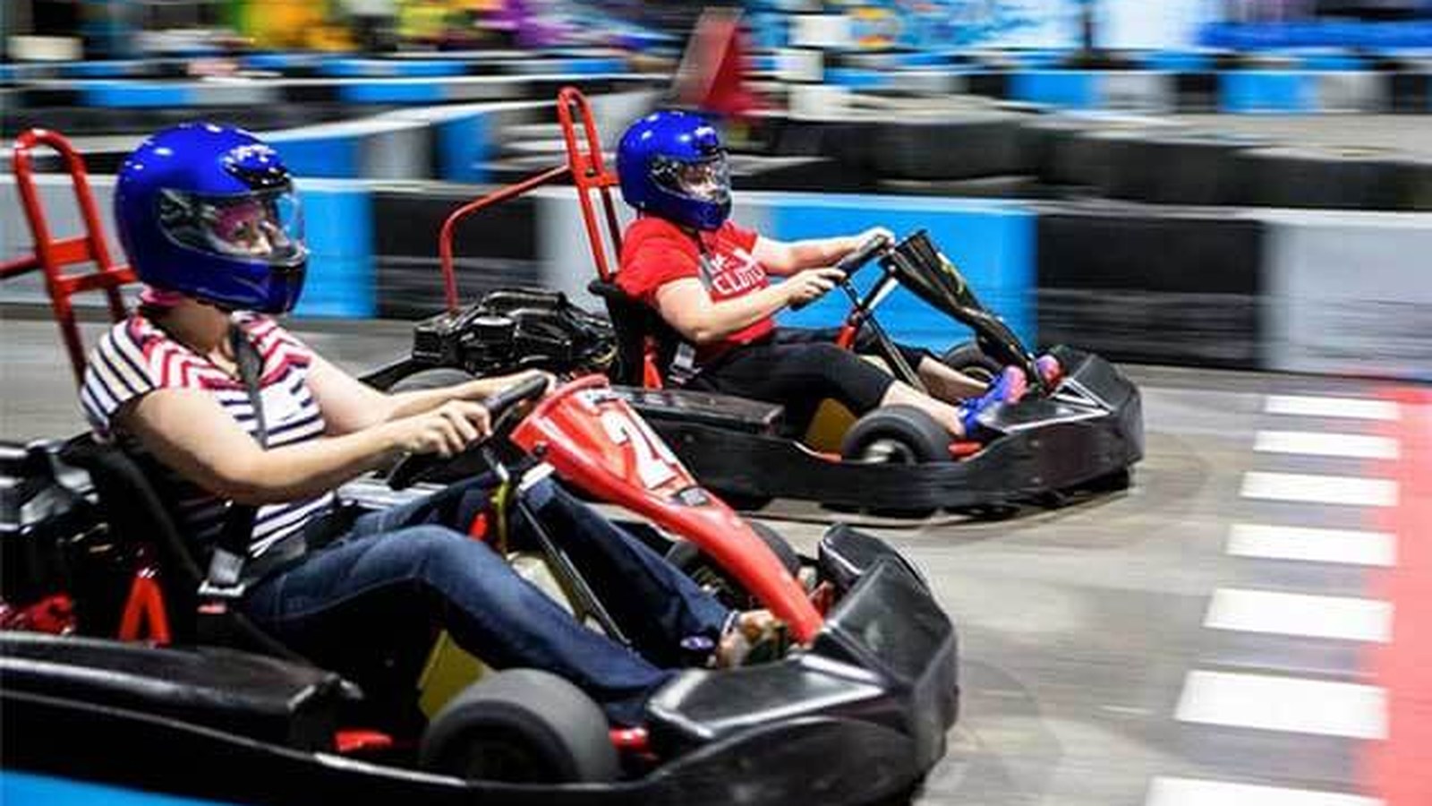 Two boys racing go-karts on the indoor asphalt track at Xtreme Action Park in Fort Lauderdale