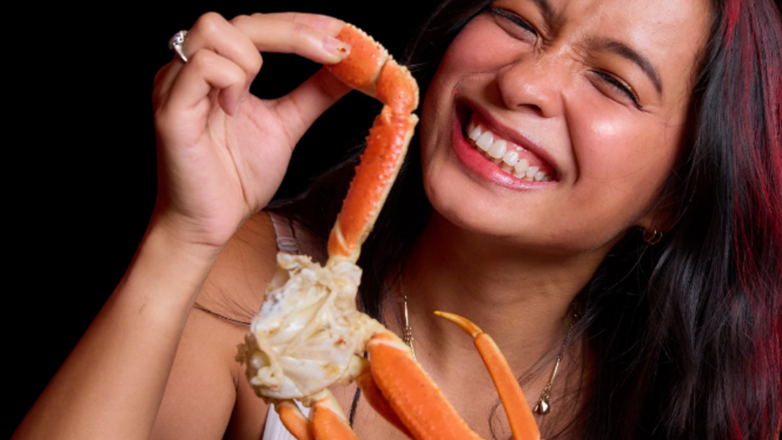 Woman enjoying crab legs and premium meats at Chow One Korean Steakhouse tabletop grill