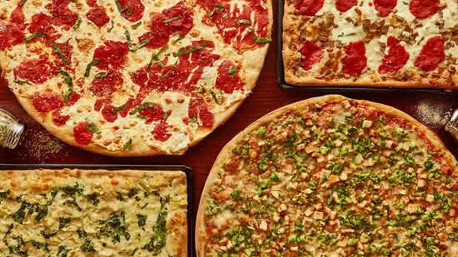 Cheese pizza slice with golden-brown crust, melted mozzarella, and fresh herb garnish at Joe's Pizza & Pasta